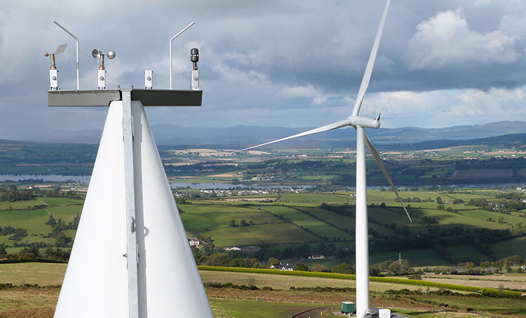 Image of the propellers on a wind turbine with country side landscape in background