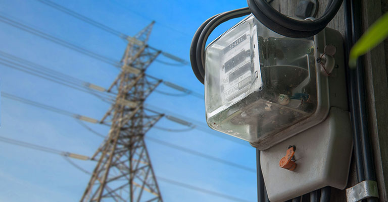 Close up photograph of a meter with a pylon in the background