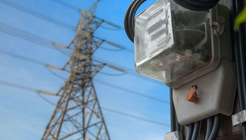 Close up photograph of a meter with a pylon in the background