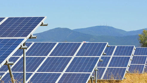 Photograph of a row of solar panels with mountains in the background