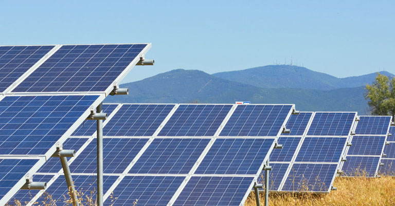 Photograph of a row of solar panels with mountains in the background