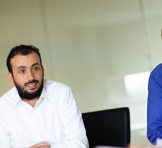 stratigic-adv-solutions-carousel Image of two men in a meeting room listening to another man speak
