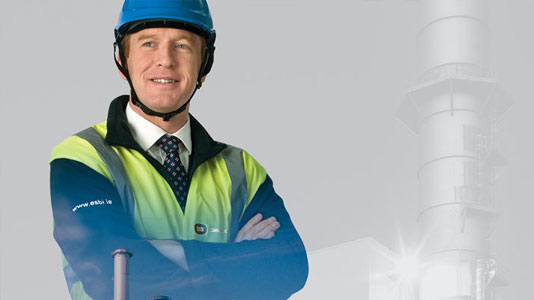 Photograph of a smiling man in a hard hat with his arms folded. A faded image of an energy plan is superimposed on top of him