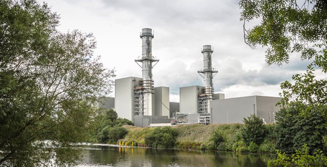 Image of two chimneys on a power station with a river and trees in the foreground